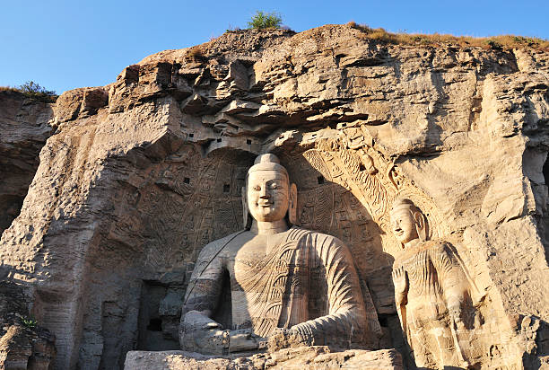 Big seated Buddha statue in Cave 20 & smaller seated Buddha in Cave 19 at Yungang Grottoes, Datong, Shanxi, China. Created in 5th century during Northern Wei period. UNESCO World Heritage.