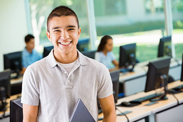 istock Teen boy smiling in high school computer lab 482859259