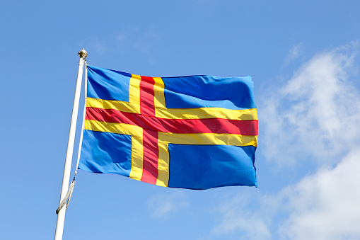 Close-up of the Aland Islands flag on blue sky.