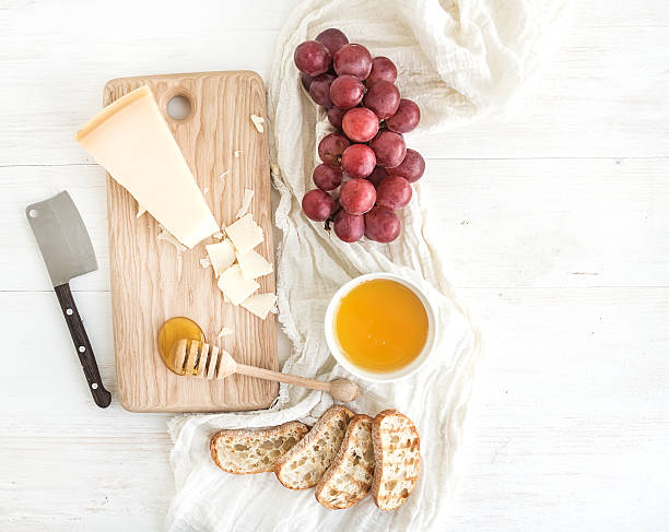 Parmesan cheese with grapes, honey and bread slices on wooden
