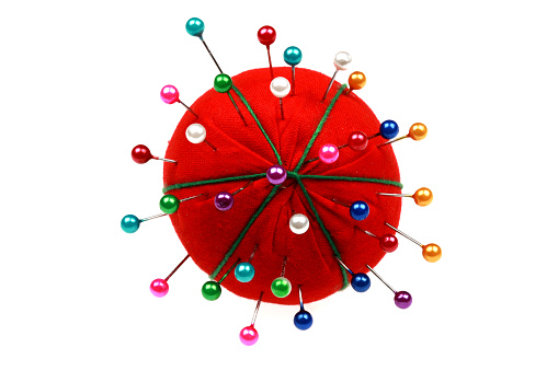 Red Pin Cushion With Coloured Pins, isolated against a white background