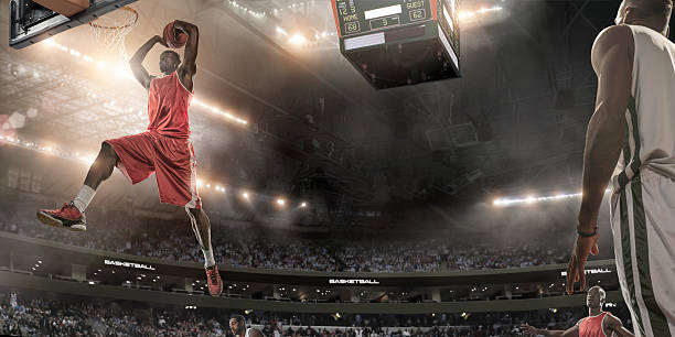 Basketball Player About To Slam Dunk Professional basketball player about to score during game in indoor floodlit basketball arena full of spectators making a basket scoring stock pictures, royalty-free photos & images