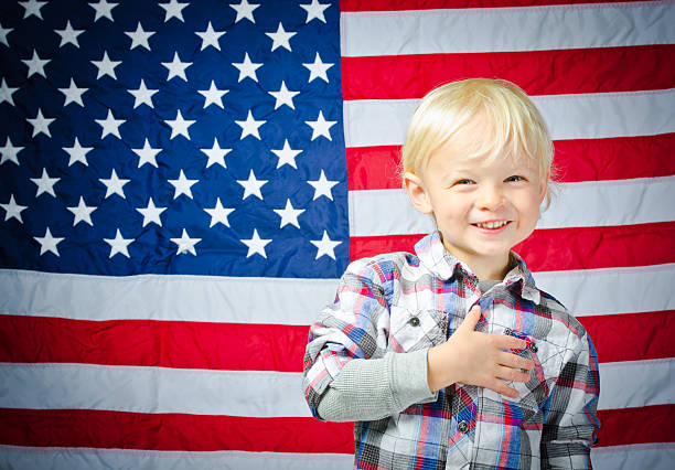 istock Happy, Young Boy Smiling and Standing by American Flag 482884517