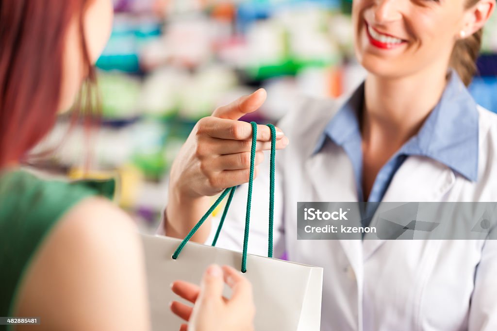 Feminino farmacêutico NA a farmácia com um cliente - Foto de stock de Farmácia royalty-free