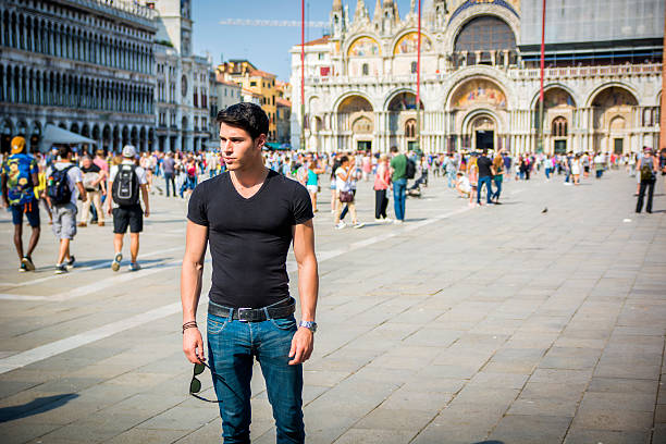 Young Man in San Marco Square in Venice, Italy, wearing black t-shirt and looking away to a side