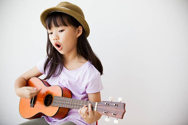 little chinesische mädchen singen und spielen ukulele - uke stock-fotos und bilder