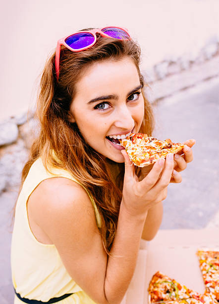 istock Smiling girl biting into slice of pizza 482900165