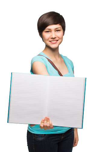 Confident schoolgirl showing notebook and holding a textbook isolated over white background