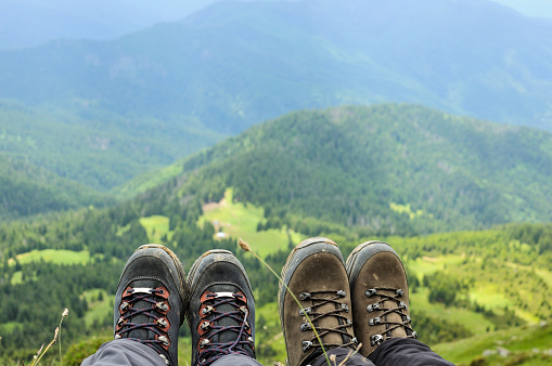 Hiking boots of traveler sitting on high mountain top in travel. Freedom concept