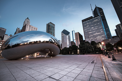 Chicago, IL, United States - October 10, 2014:Chicago Cloud Gate sculpture and downtown Chicago skyline buildings in Millenium Park at early morning