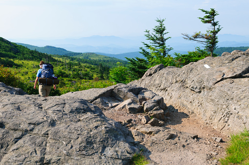 A young woman backpacks on the Appalachian Trail in southwest Virginia, part of a three-day hike that began in Grayson Highlands State Park at Elk Garden, on Highway 600. The white blaze is a trail marker indicating the path of the Appalachian Trail.