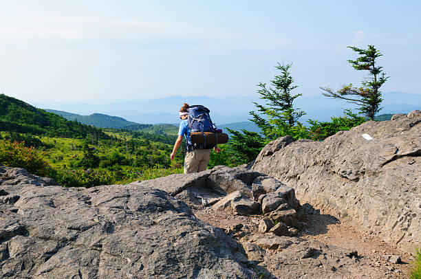 A young woman backpacks on the Appalachian Trail in southwest Virginia, part of a three-day hike that began in Grayson Highlands State Park at Elk Garden, on Highway 600. The white blaze is a trail marker indicating the path of the Appalachian Trail.