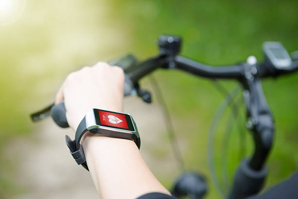 mujer montando una bicicleta con un monitor smartwatch la frecuencia cardíaca. - human cardiovascular system heart shape human hand healthy lifestyle fotografías e imágenes de stock