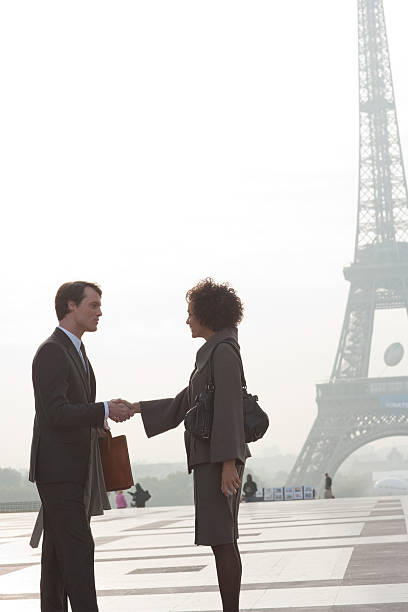 dois empresários agitando as mãos ao ar livre da torre eiffel - accords imagens e fotografias de stock