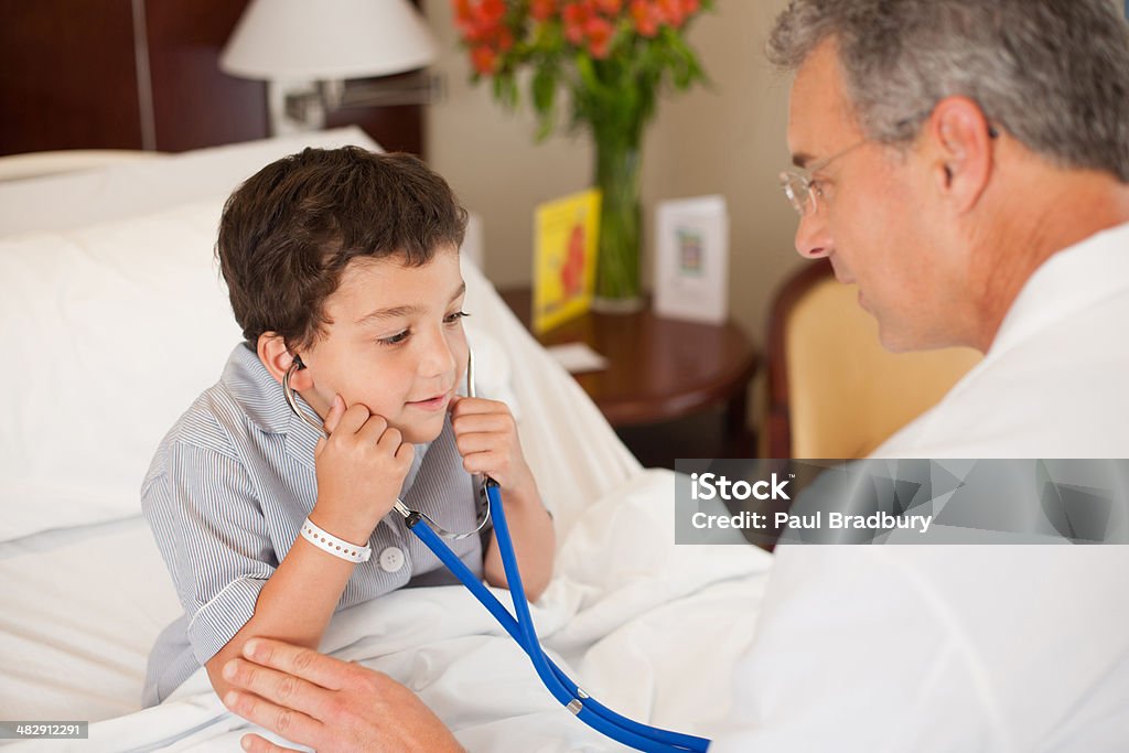 Doctor and young patient in hospital room playing with stethoscope and smiling  4-5 Years Stock Photo