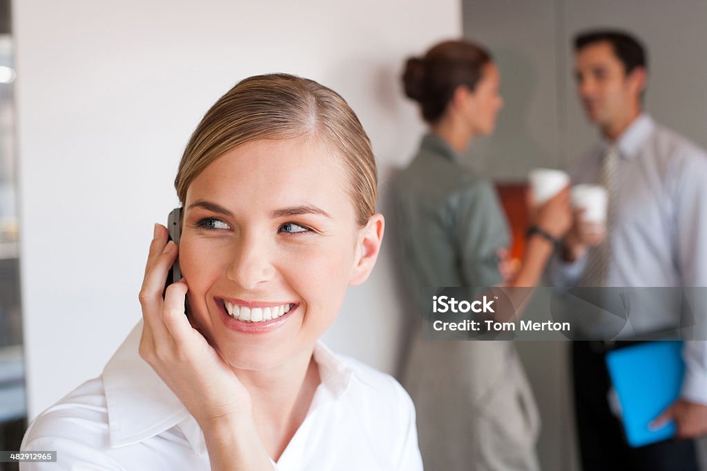 Geschäftsfrau Gespräch am Telefon mit Kollegen im Hintergrund - Lizenzfrei 20-24 Jahre Stock-Foto