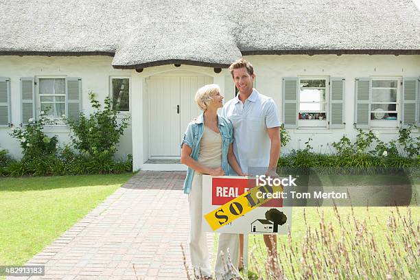 Man And Woman Outdoors In Front Of House With Sold Sign Stock Photo - Download Image Now