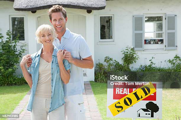 Man And Woman Outdoors In Front Of House With Sold Sign Stock Photo - Download Image Now