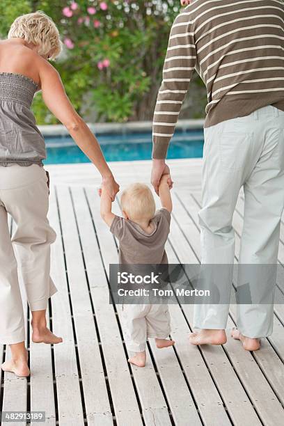 Man And Woman Teaching Boy To Walk Stock Photo - Download Image Now - Family, Swimming Pool, 12-17 Months