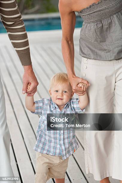 Man And Woman Teaching Boy To Walk Stock Photo - Download Image Now - 12-17 Months, 30-39 Years, 35-39 Years