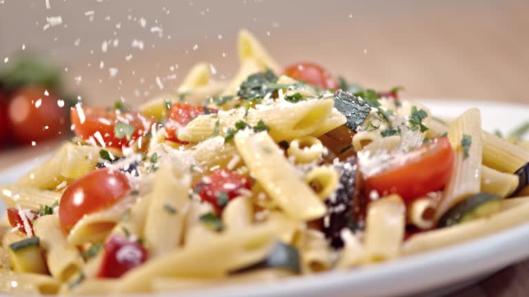 SLO MO Sprinkling parmesan over pasta with fresh vegetables