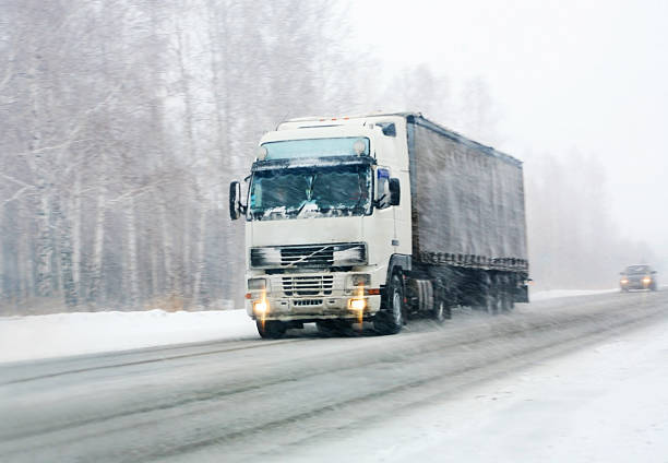 Freight transportation truck on the road in snow storm blizzard, bad weather conditions for transportation event, selective focus