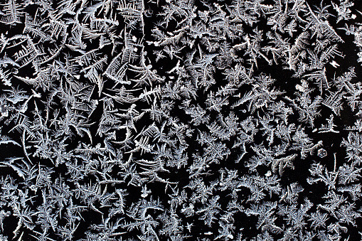 Real frost crystals on a black surface.   This image makes a great background or texture layer to overlay and add a frost effect to any image.