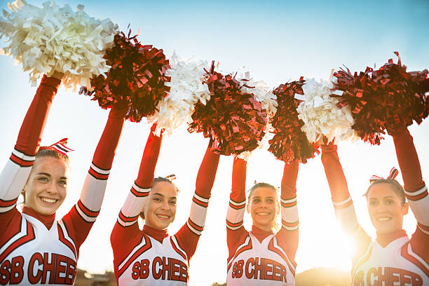 szczęście cheerleaderki pozujących z pon-pon i ręce podniesione - cheerleader zdjęcia i obrazy z banku zdjęć