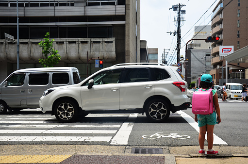 Kyoto, Japan - July 11, 2015: Children japanese girl waiting cross over road at crosswalk traffic road in Kyoto, Japan