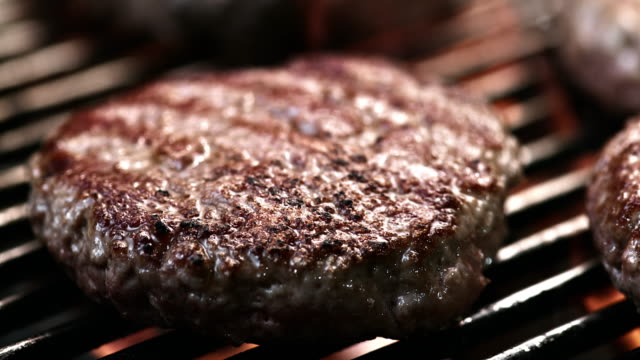 SLO MO LD of beef burger sizzling on a grill