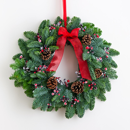 Advent wreath with red ribbon over bright wall