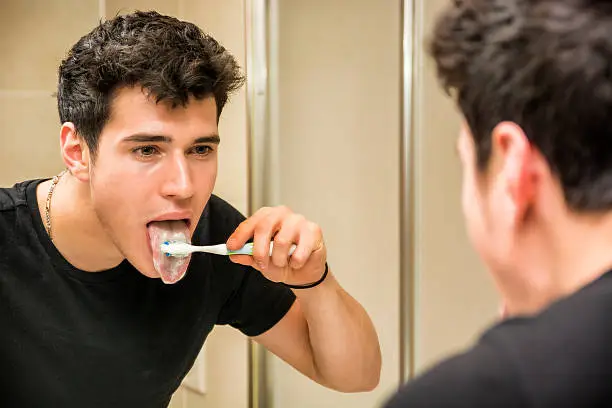 Photo of Headshot of attractive young man brushing teeth and tongue