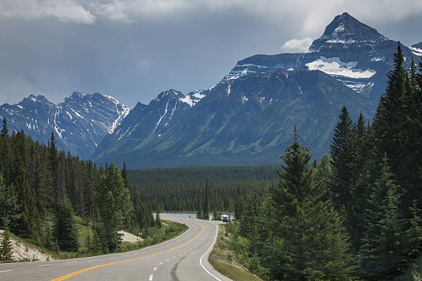 istock Mountain road with forest and snowy peaks 482938594