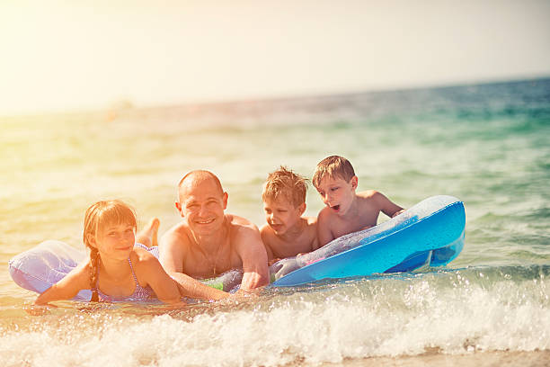 istock Father and kids having fun in sea on air bed 482938782