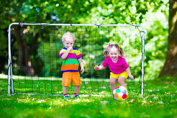 маленькие дети, играя в футбол в школьном дворе - playing field goalie soccer player little boys стоковые фото и изображения