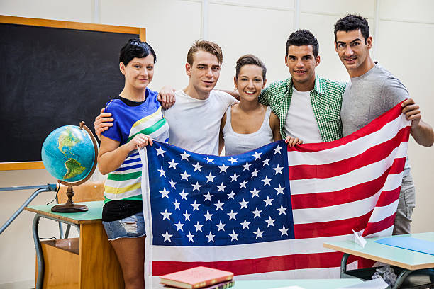 lächelnd studenten im klassenzimmer halten uns flagge - adolescence flag university people stock-fotos und bilder