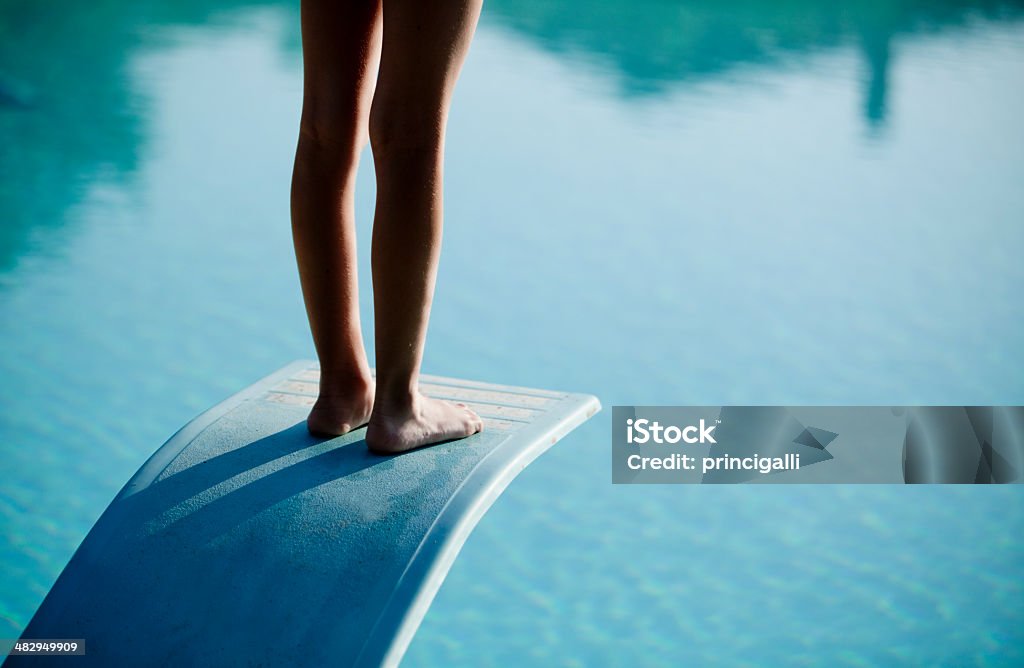 Plan des jambes nues à plongeoir au-dessus de l'eau bleue - Photo de Courage libre de droits