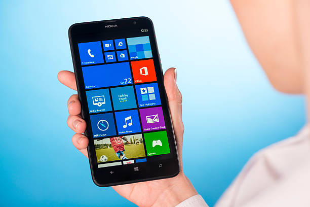 Koszalin, Poland - March 21, 2014: Woman hand holding an Lumia 1320. Devices display home screen. Close-up shot on Lumia 1320. The Lumia 1320 is smartphone with multi touch screen produced by Nokia.