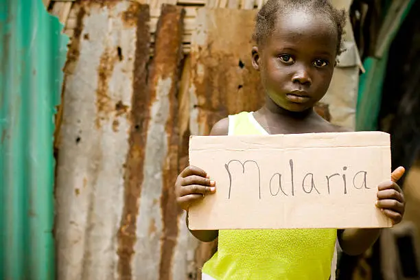 An African girl holding a sign with 'Malaria' written on it.