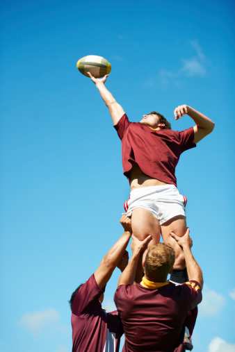 A rugby player being lifted up and catching the ball