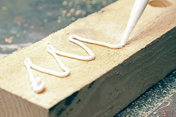 putting glue on a piece of wooden board