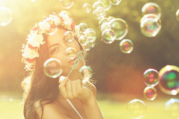 Young woman having fun and blowing bubbles outdoors stock photo