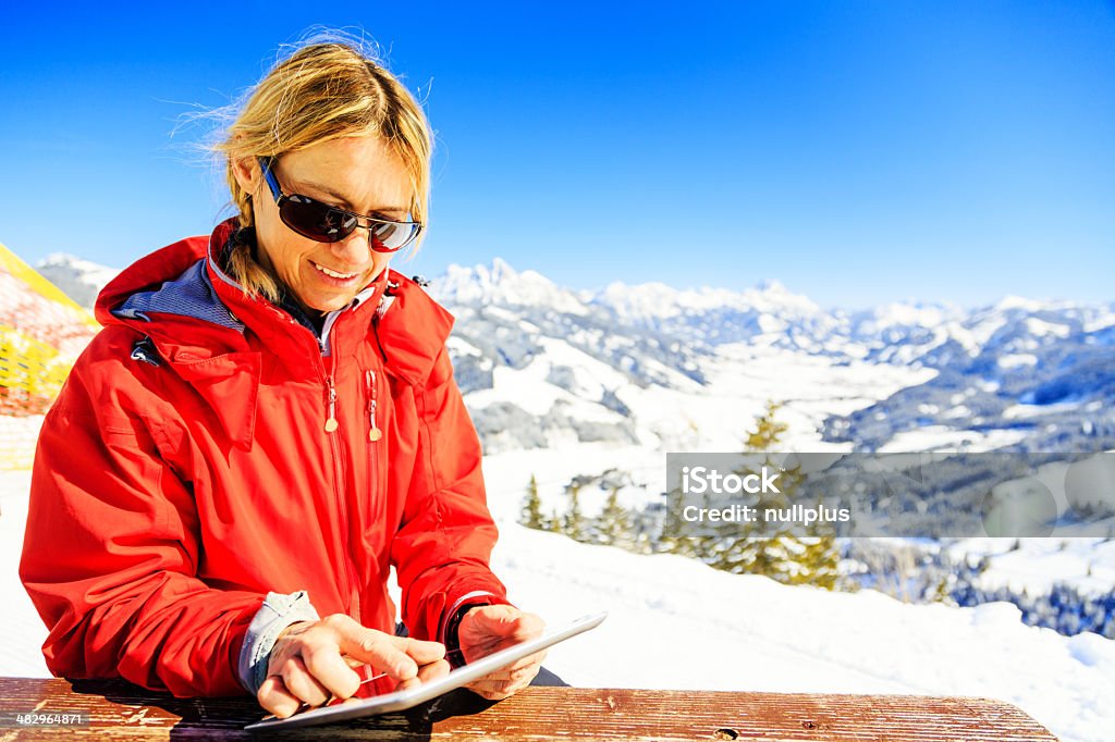 mature woman with digital tablet mature woman with digital tablet in the alps, checking the weather forecast Digital Tablet Stock Photo