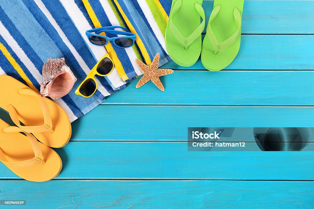Beach scene with blue wood decking Beach scene with striped towel, sunglasses, flip flops, seashell and starfish laid on old weathered blue wood decking.  Space for copy.   Alternative version with sand shown below: Backgrounds Stock Photo