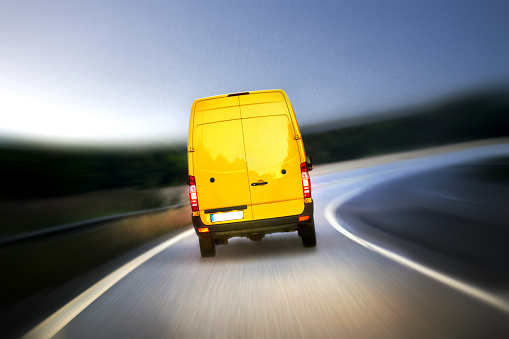 Close up of a motion blurred delivery van service vehicle, on highway with clean, blank rear side and copyspace in the image. Clear blue sky at dusk. More service vehicles, and cars in my portfolio