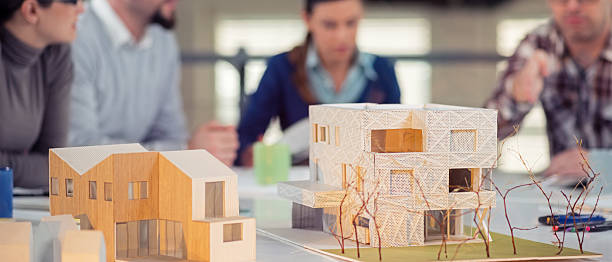 Young Architects Working Together Team of young architects working on a home project in the studio, model houses in front. architectural model photos stock pictures, royalty-free photos & images