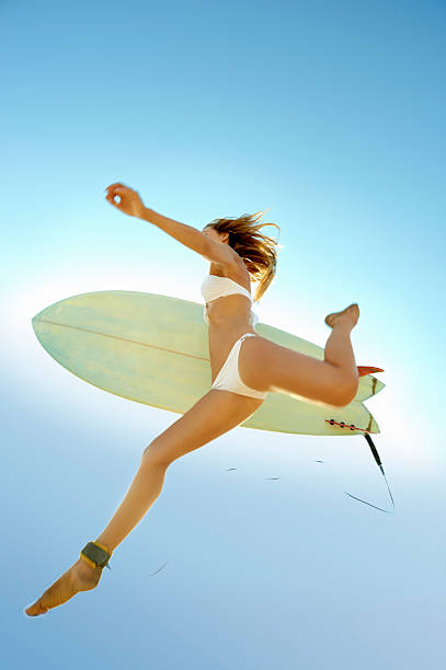 Young surfer jumping through sky with surfboard stock photo
