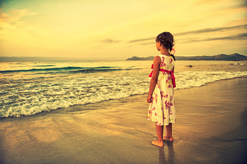 Little girl enjoying sea view in the evening.