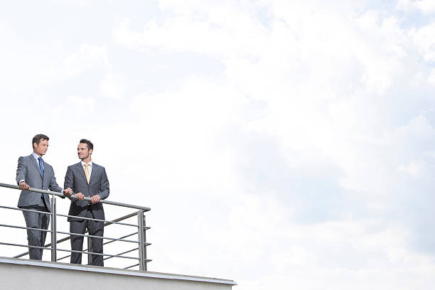 istock Businessmen standing at terrace railings against cloudy sky 482970795