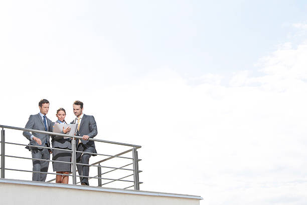 istock Businesspeople standing at terrace railings against sky 482970811
